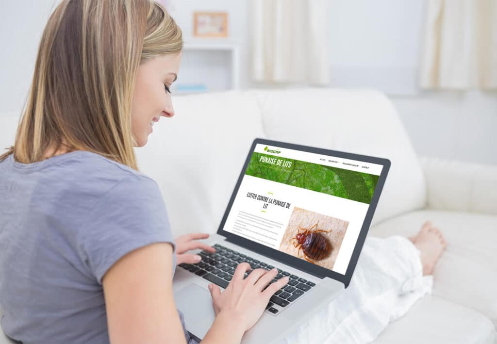 Traitement punaises de lit : Conseils et solutions Biocap Femme consultant le site Biocap pour lutter contre les punaises de lit sur son ordinateur portable dans son salon.